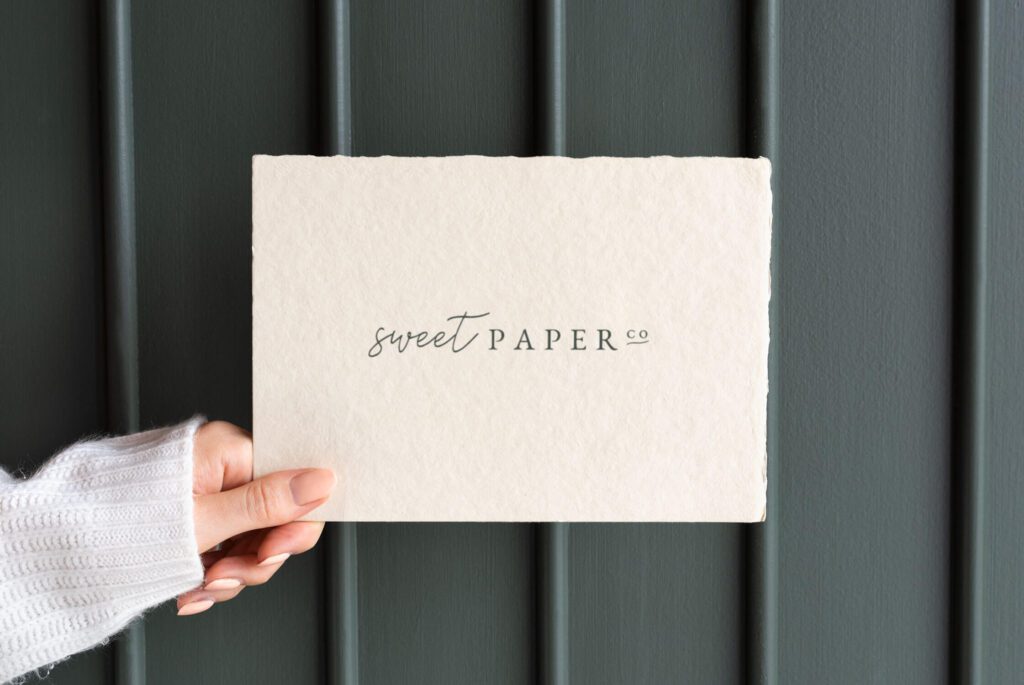 woman's hand holding paper with sweet paper co logo